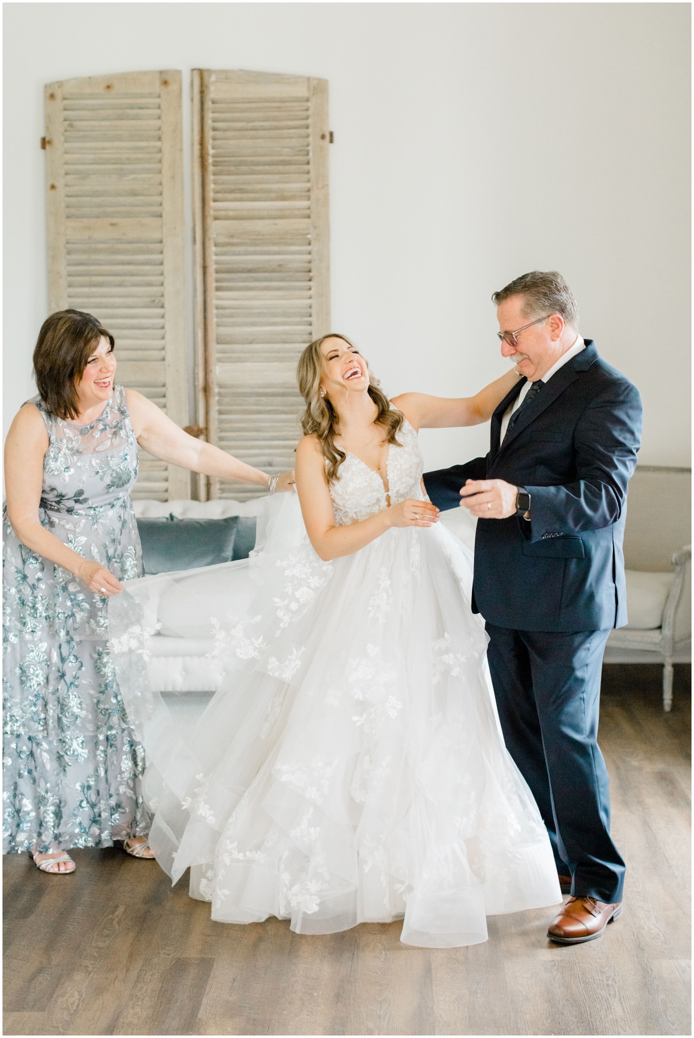 a bride is laughing with her parents on her wedding day 