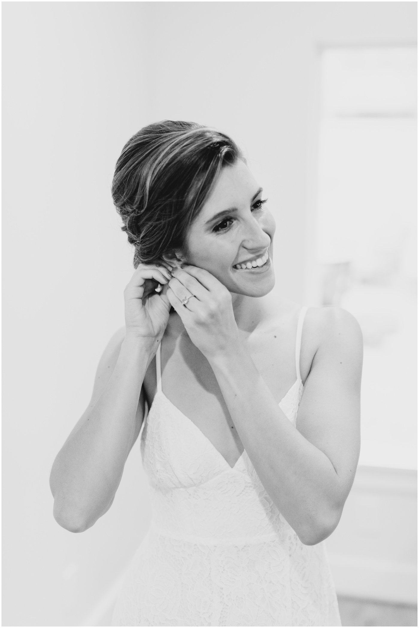 a bride putting in her earrings and smiling