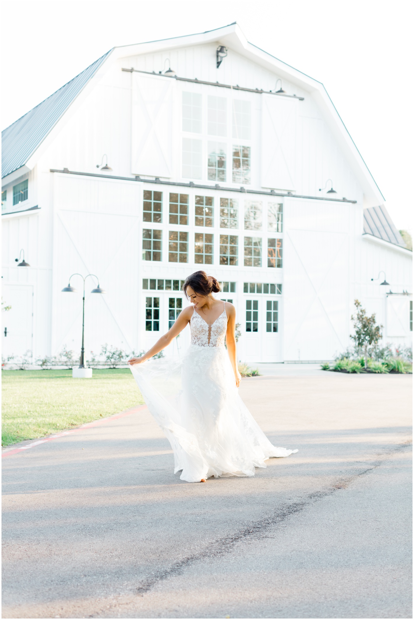 a bride walks while holding her dress and the sun glows behind her