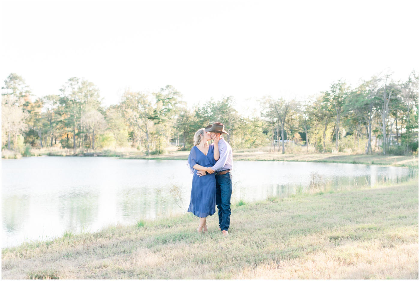 a couple kiss by the pond at sunset during their engagement session in Texas 