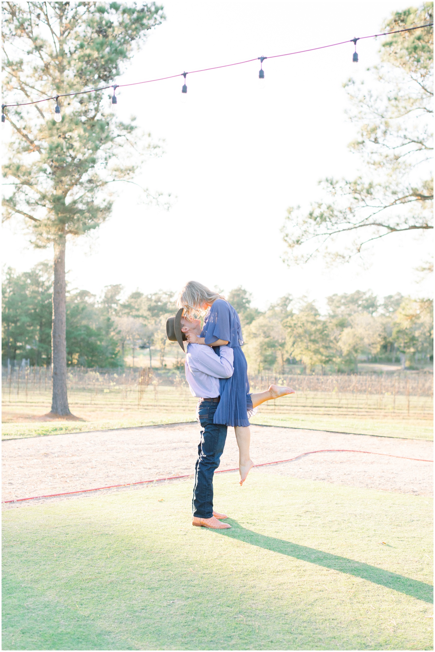 a man lifts his fiance as they dance together at their Texas engagement session