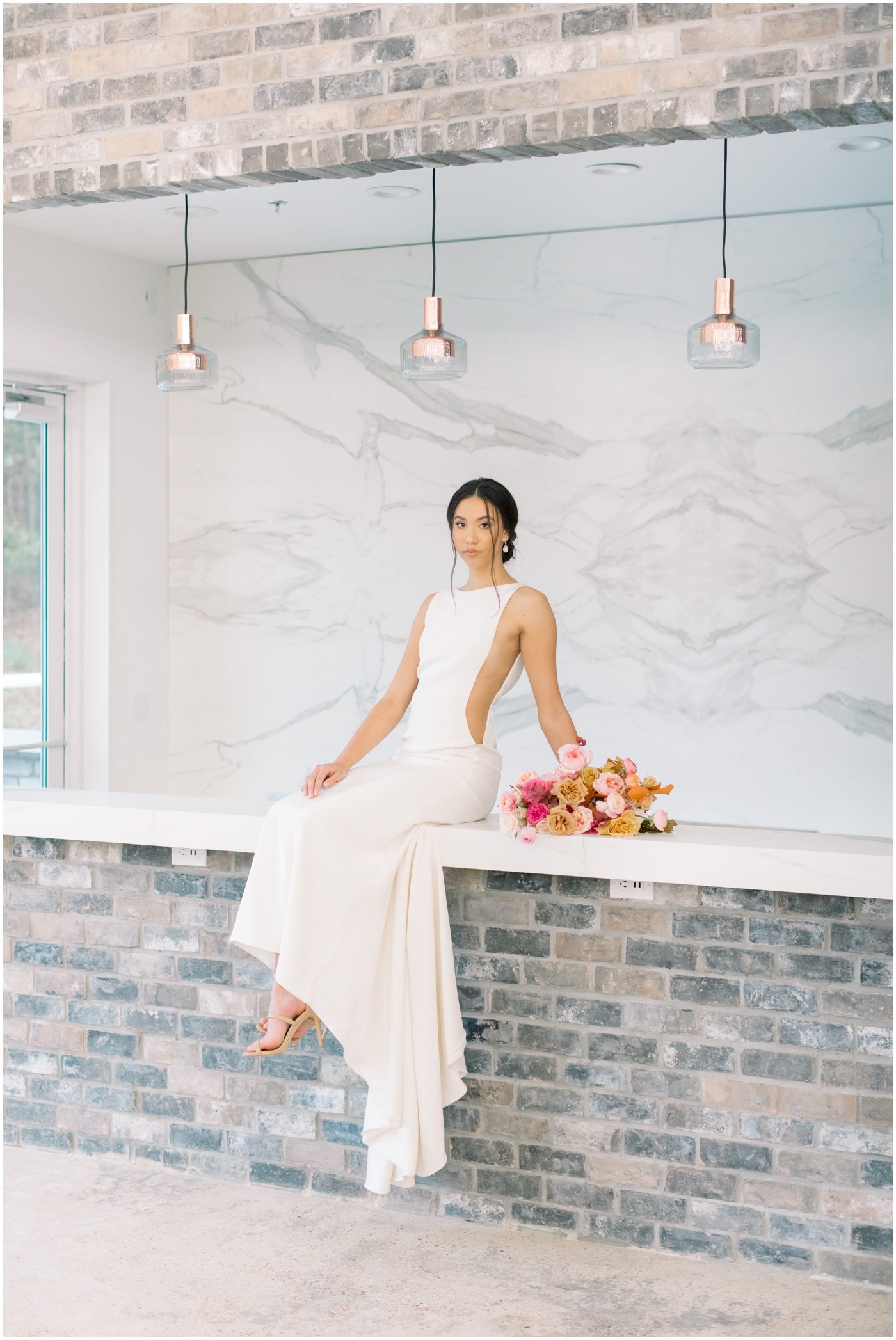a bride sitting with her bouquet on a bar