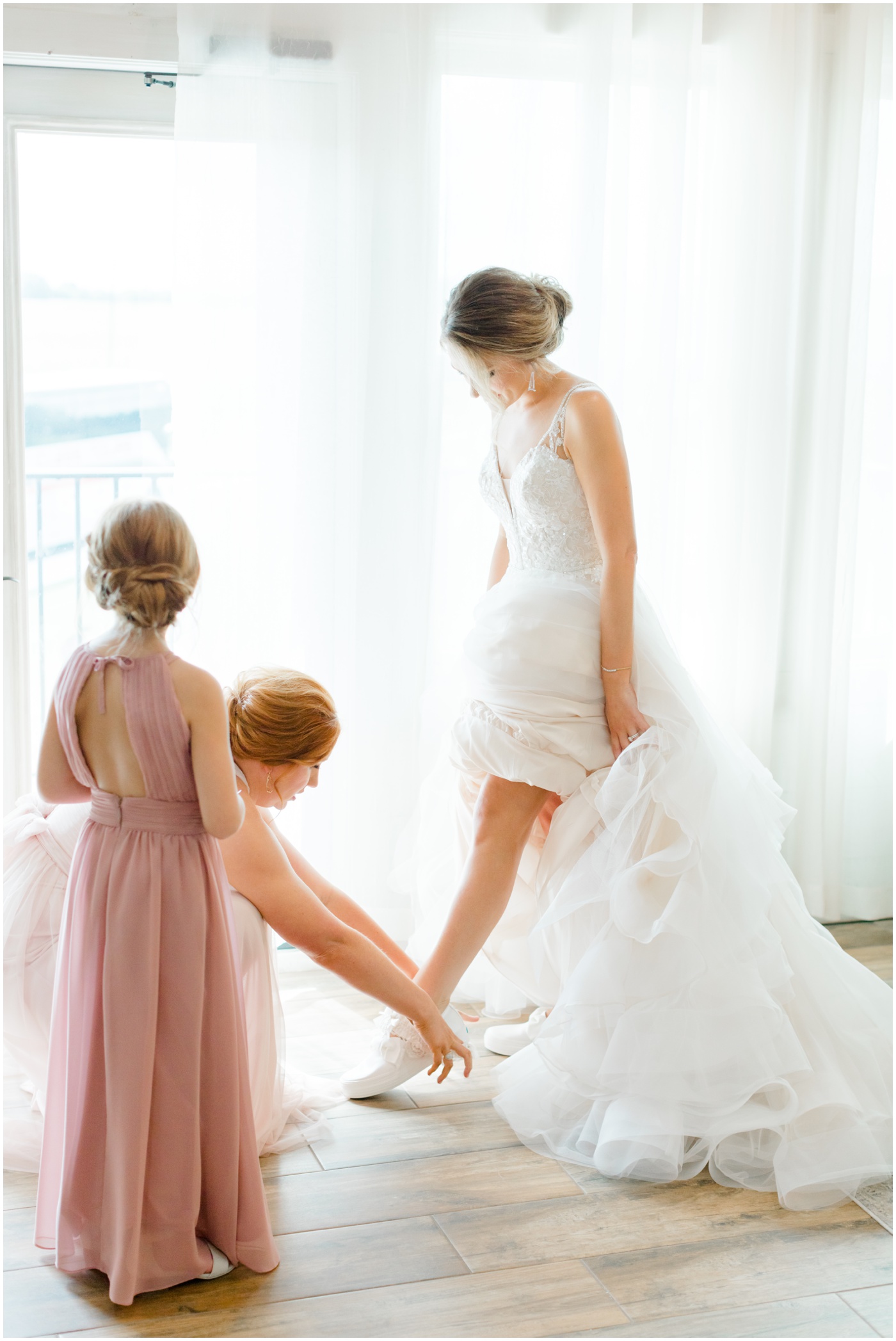 bride's sister helping her put on shoes