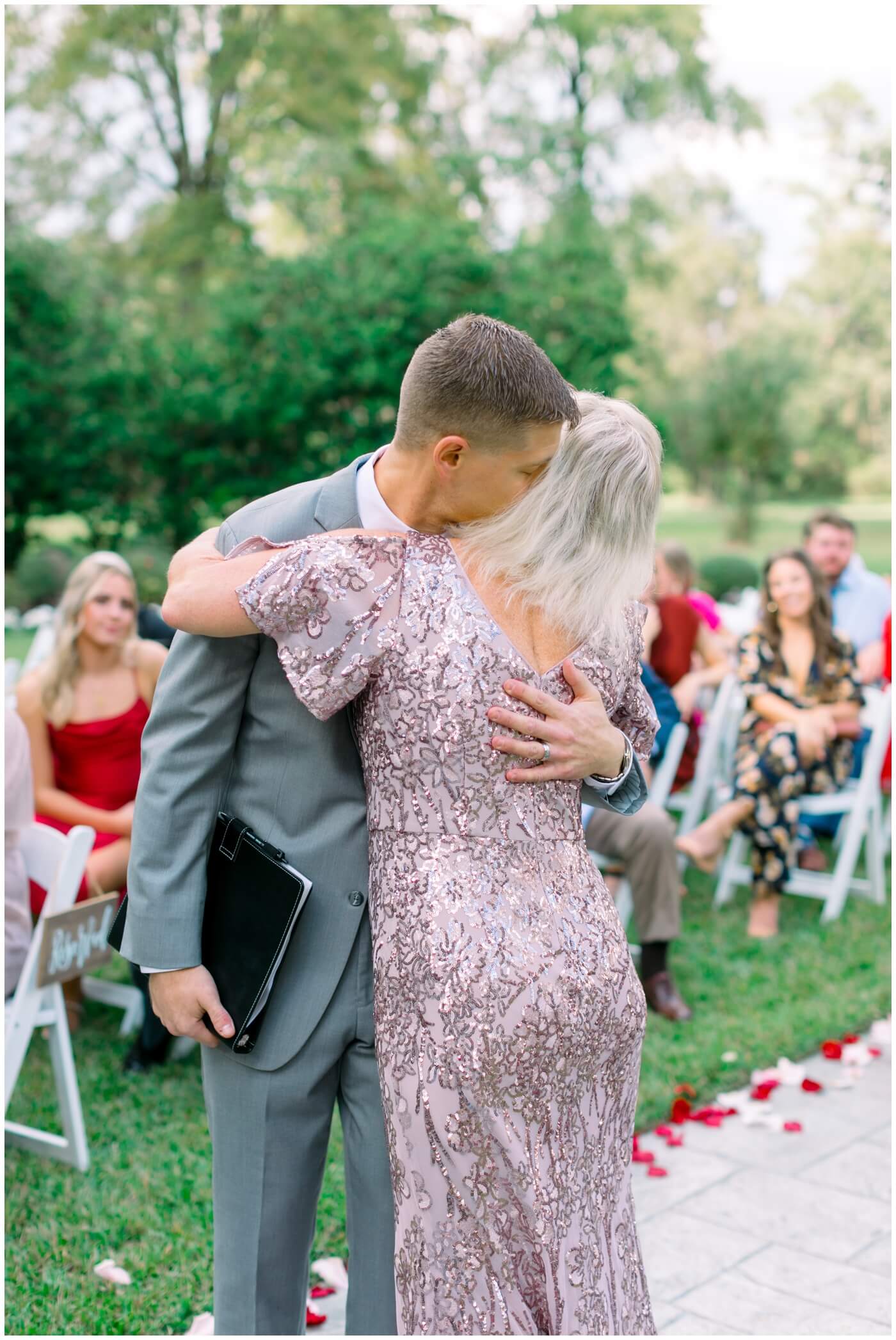 the officiant and brother of the bride hugs his mom
