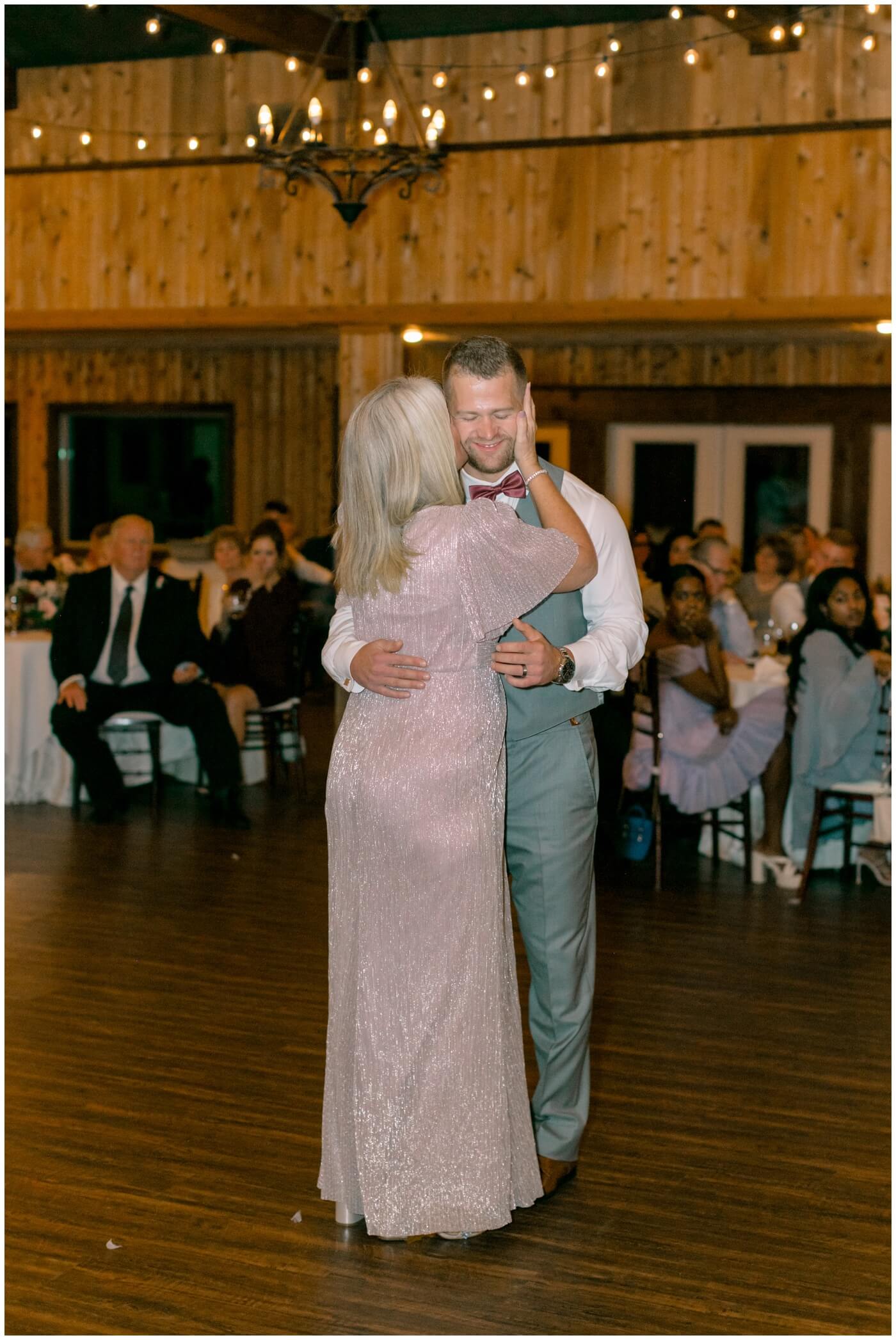 the grooms mom kisses his cheek while they dance 