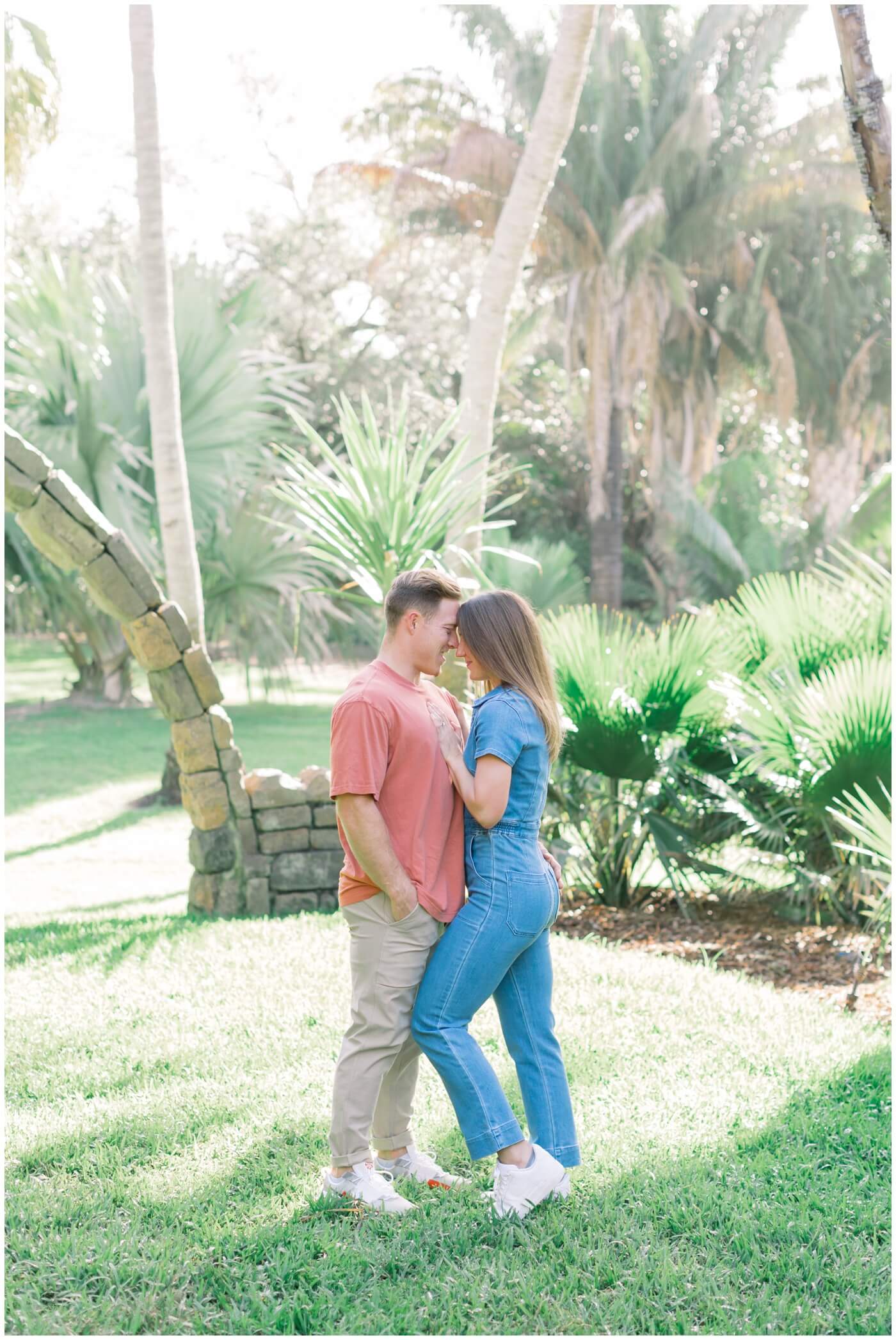 a couple snuggles up close at the botanical gardens in miami during their engagement session.