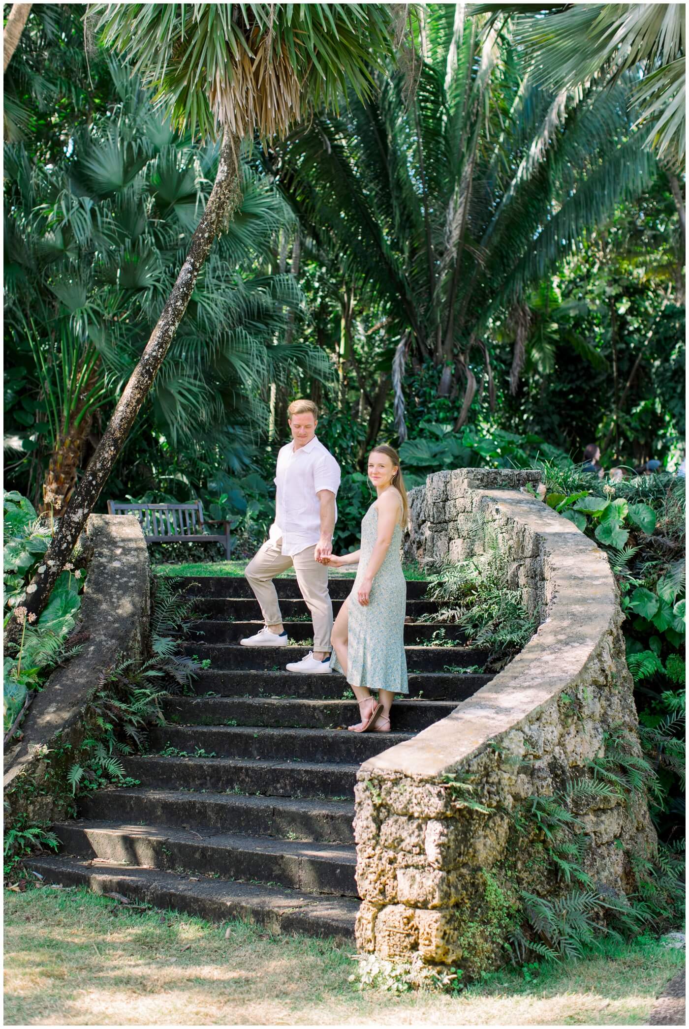 a couple stands on stone stairs and grin during their destination engagement session