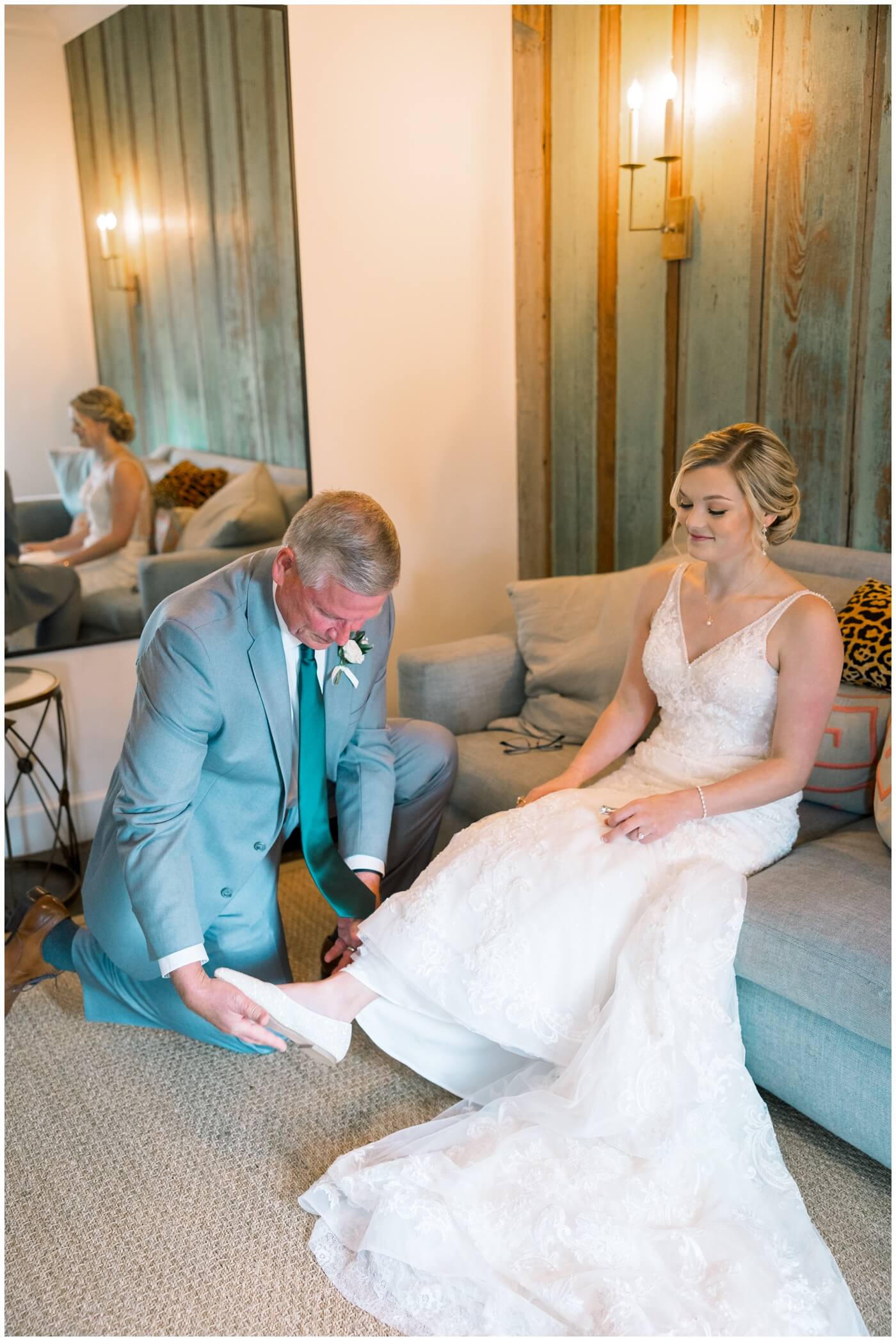 The brides dad helps his daughter put her wedding shoes on