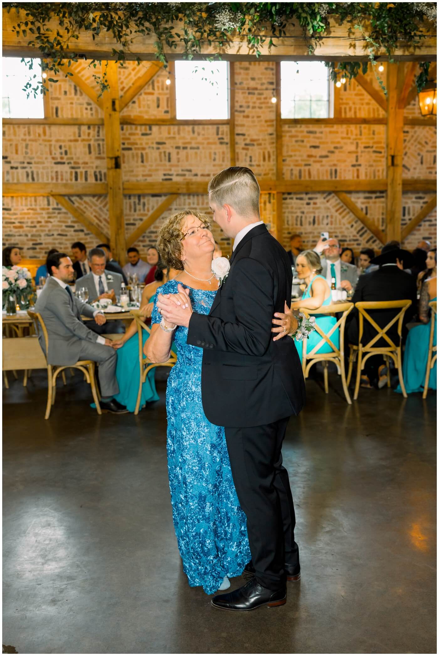 The groom smiles at his mom as they dance together on his wedding day 