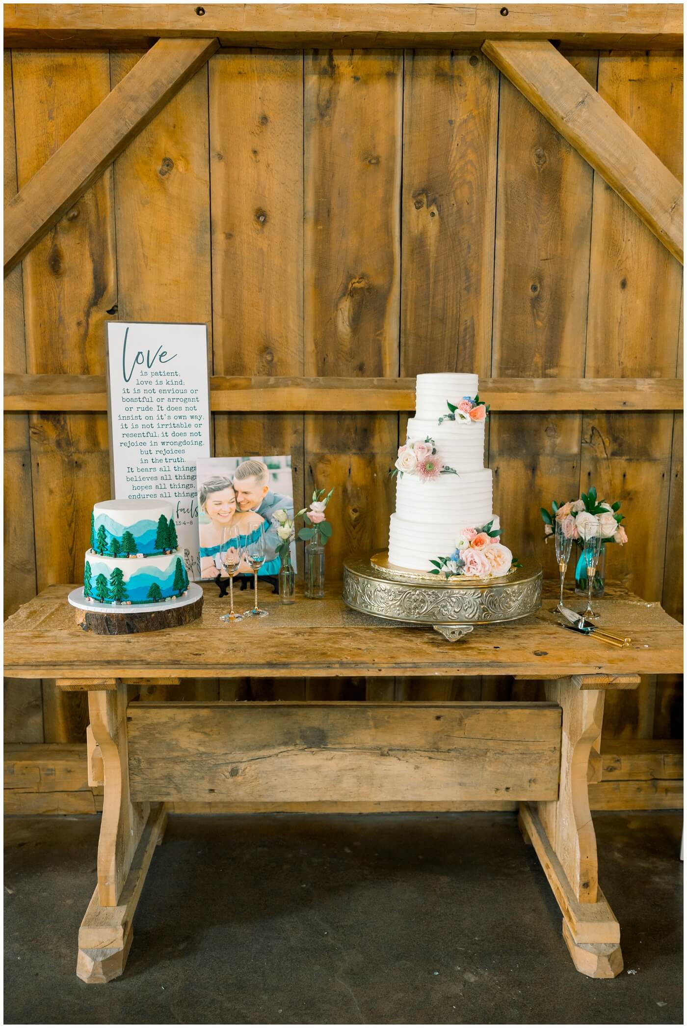 The cake table is beautifully prepared with flowers and greenery