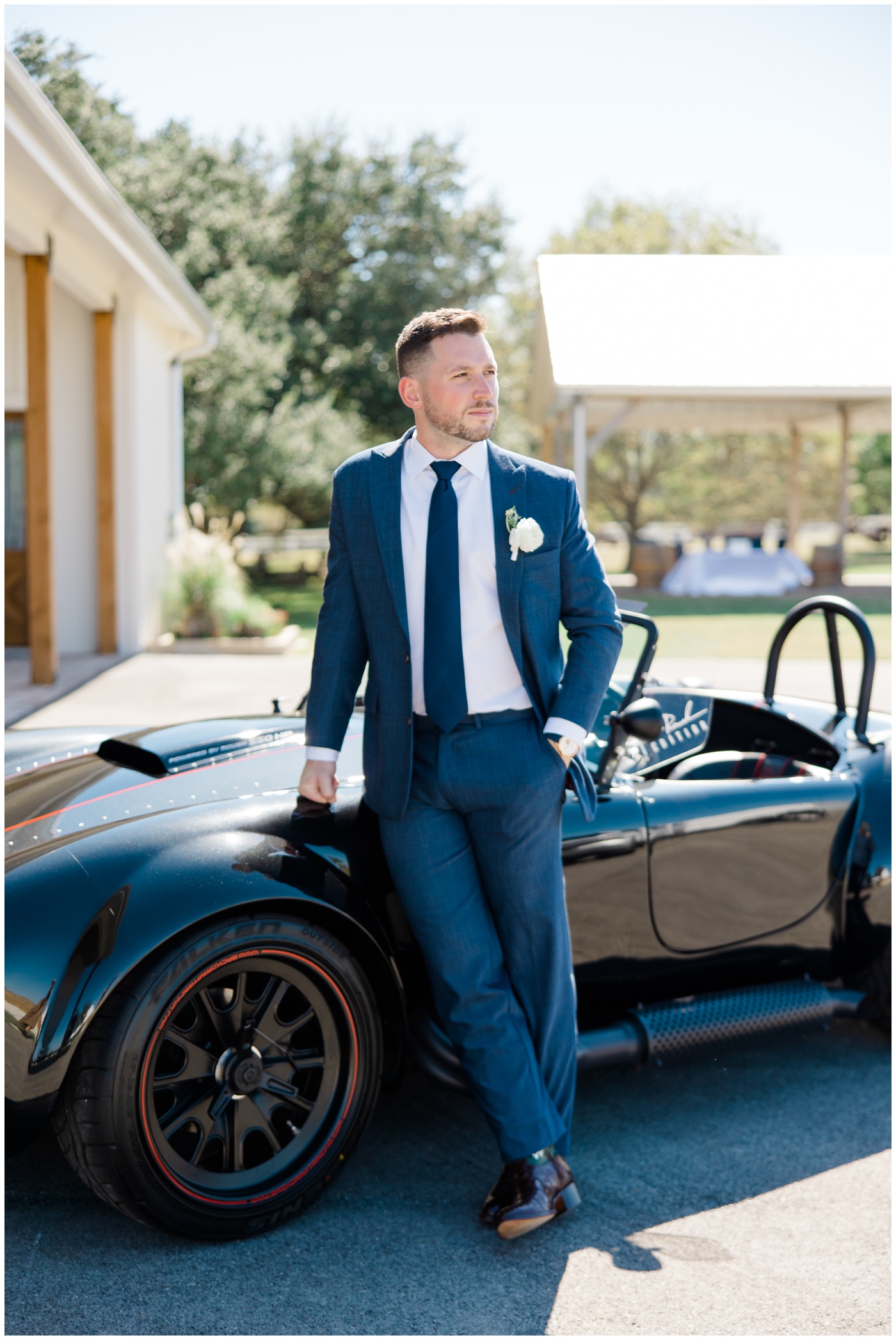 Houston Wedding Photographer | A groom stands beside a sports car on his wedding day.