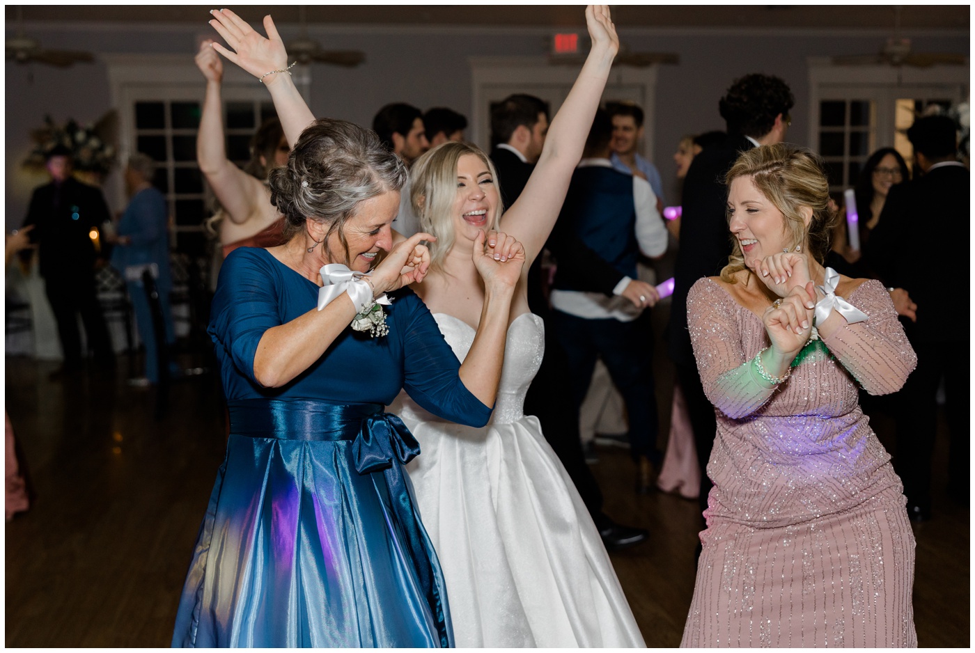 The bride dances with her mom and mother in law.