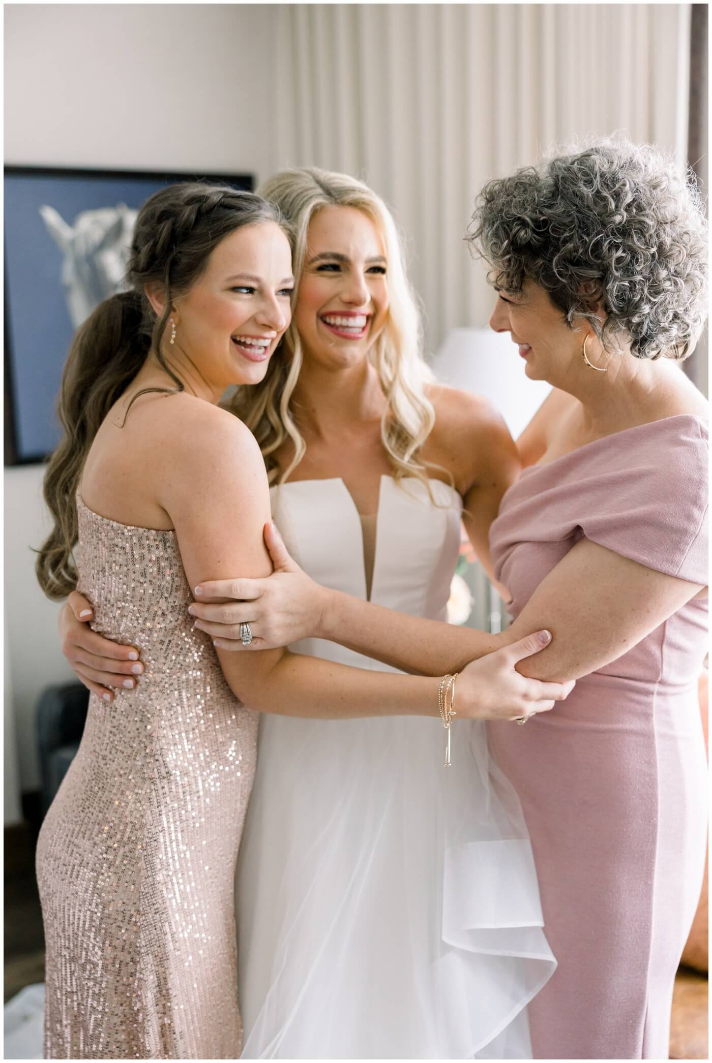Bride smiles as she hugs her mom and sister at Hotel Drover
