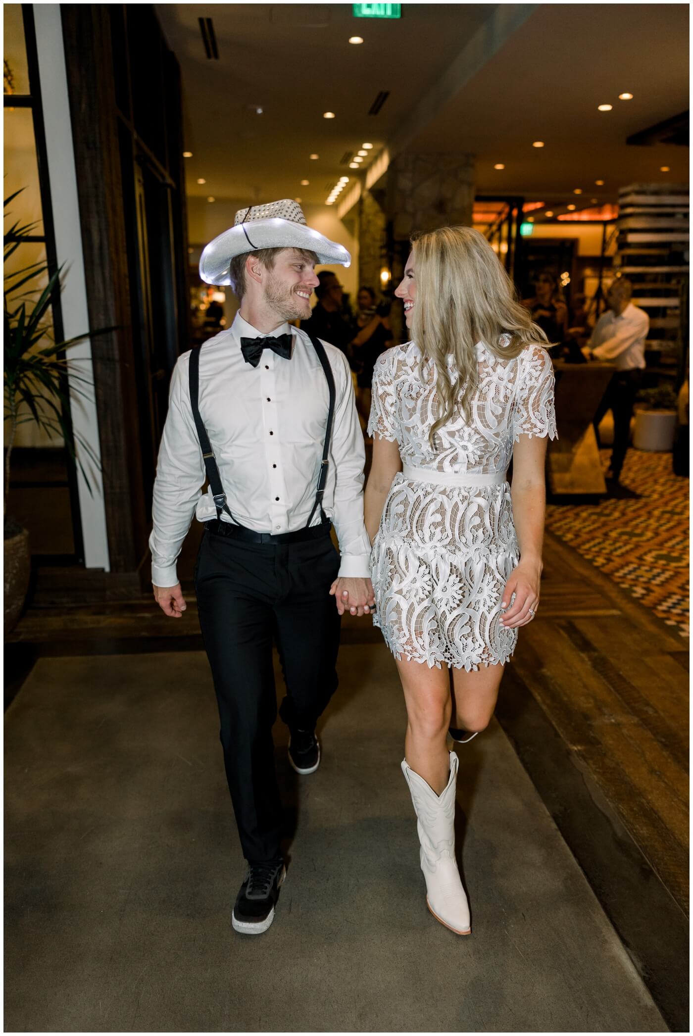Bride and groom smile as they walk through the Hotel Drover